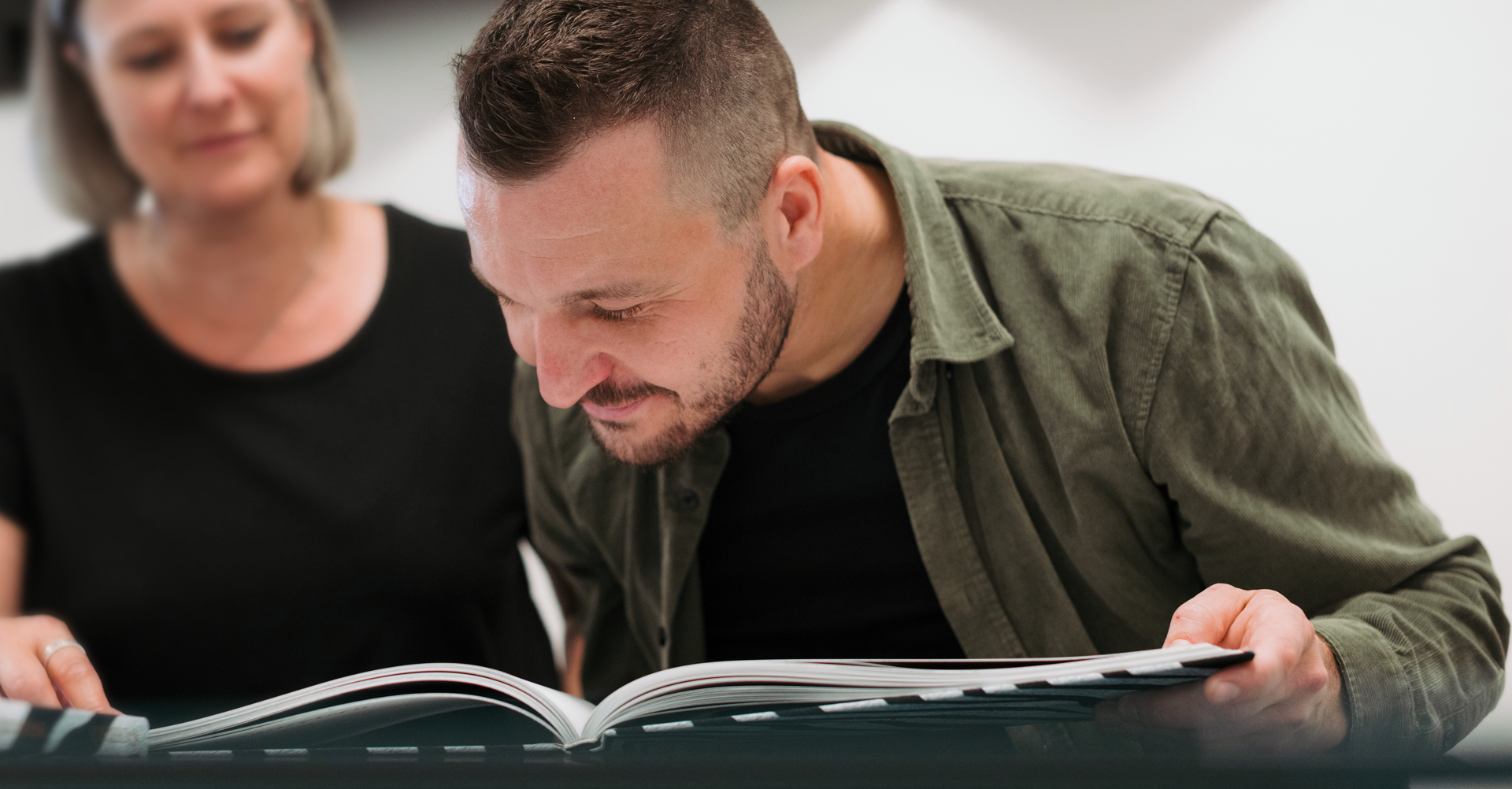 ein Mann und eine Frau beugen sich über ein Buch.